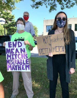 two protestors stand outside Mitch McConnell's office with signs that read "end mean Mitch's miserable mayhem" and "KY T</body></html>