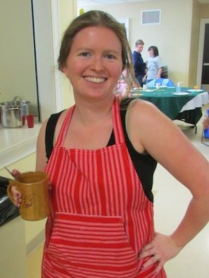 Grace is smiling at the camera while holding a coffee mug. 